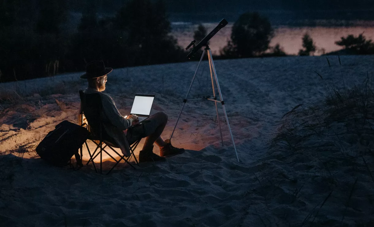 mężczyzna z laptopem na nocnym biwaku
